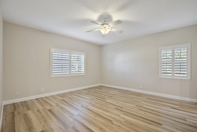 unfurnished room with a textured ceiling, light wood-type flooring, and plenty of natural light