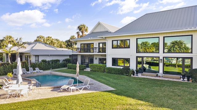 rear view of house featuring a lawn, a patio area, and a balcony