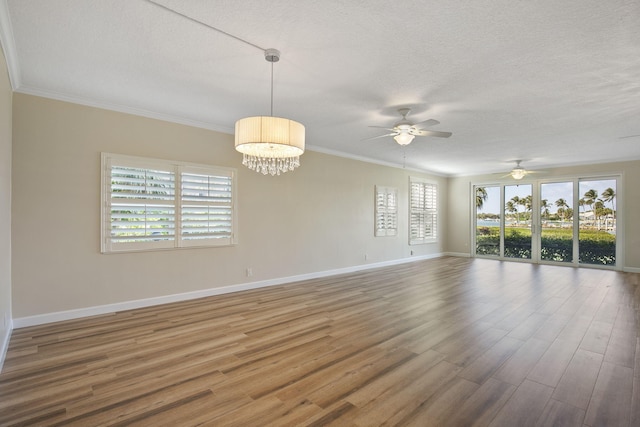 unfurnished room with ceiling fan with notable chandelier, hardwood / wood-style flooring, a wealth of natural light, and crown molding