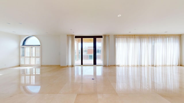 spare room featuring a wealth of natural light and light tile patterned flooring