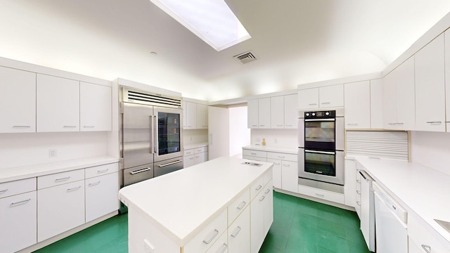 kitchen featuring a skylight, white cabinetry, a center island, and appliances with stainless steel finishes