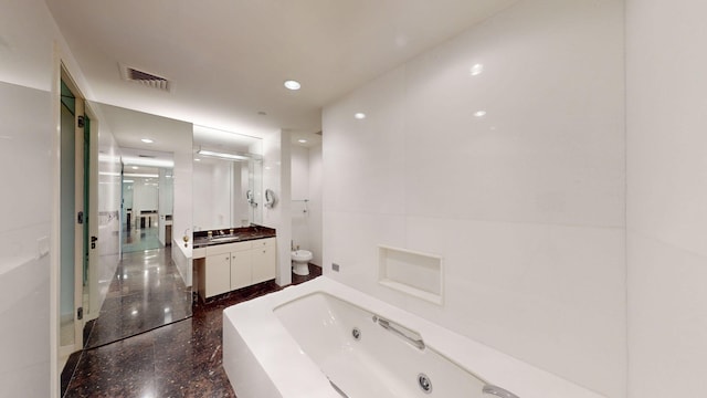 bathroom with a washtub, vanity, and a bidet