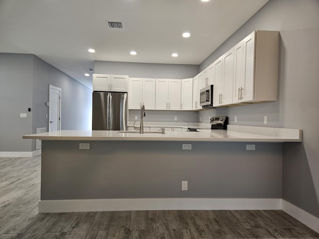 kitchen featuring kitchen peninsula, sink, white cabinets, and appliances with stainless steel finishes