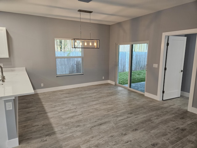 unfurnished dining area featuring a chandelier and hardwood / wood-style flooring