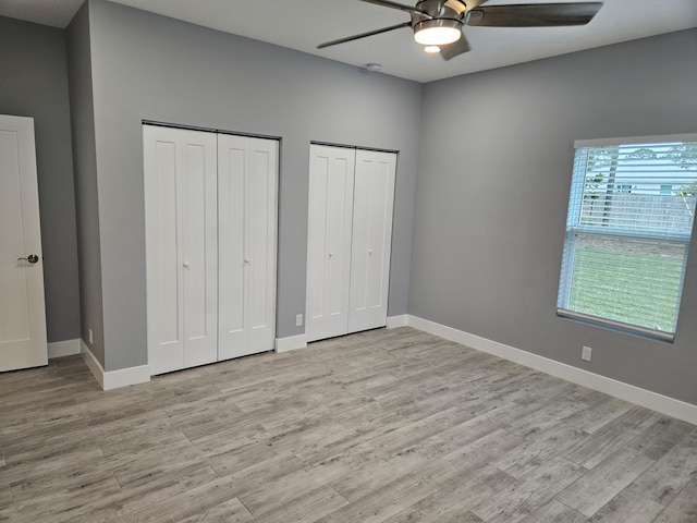 unfurnished bedroom with two closets, ceiling fan, and light hardwood / wood-style floors