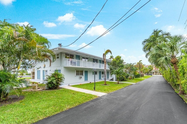 view of front of property featuring a balcony and a front yard