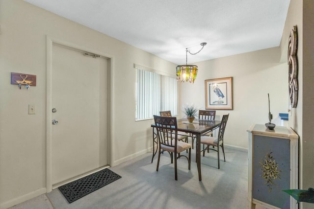 carpeted dining space with a notable chandelier and a textured ceiling