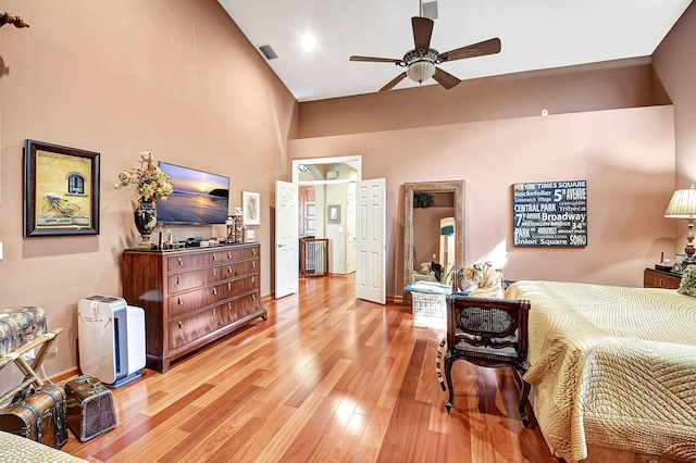 bedroom featuring ceiling fan, a high ceiling, and light hardwood / wood-style flooring