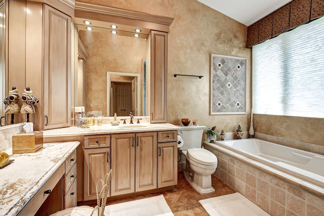 bathroom with tiled tub, vanity, and toilet