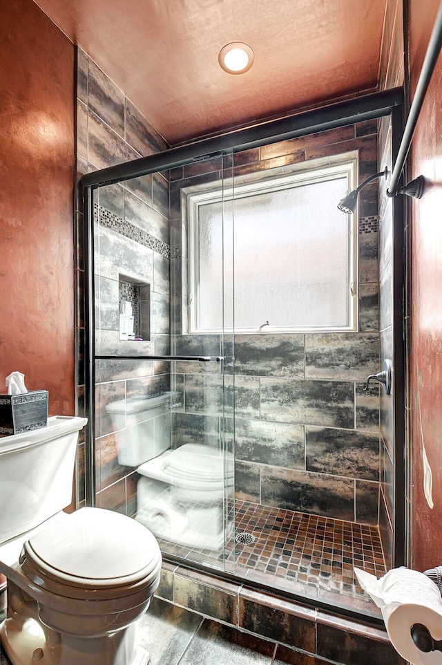 bathroom with toilet and an enclosed shower