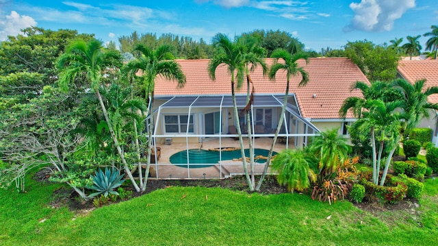 rear view of house with a lanai, a lawn, and a patio