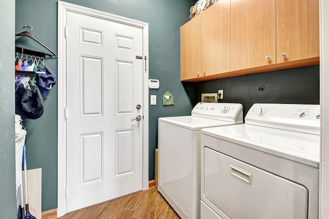 laundry area with washing machine and dryer, cabinets, and light wood-type flooring