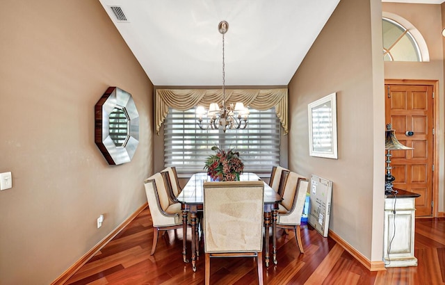 dining space with hardwood / wood-style flooring, an inviting chandelier, and vaulted ceiling