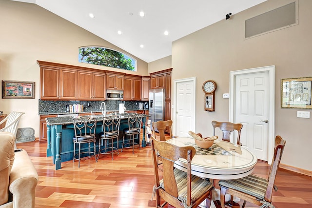 dining room with light hardwood / wood-style flooring, high vaulted ceiling, and sink