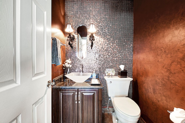 bathroom with vanity, toilet, and tile walls