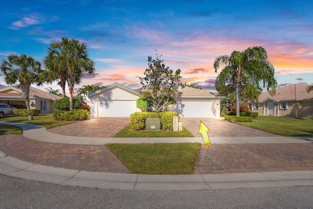 single story home featuring a garage and a yard