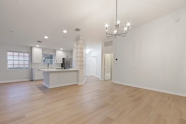 kitchen with white cabinets, stainless steel fridge with ice dispenser, light hardwood / wood-style flooring, and hanging light fixtures