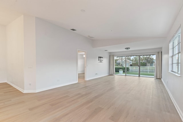 spare room with light wood-type flooring, vaulted ceiling, and plenty of natural light