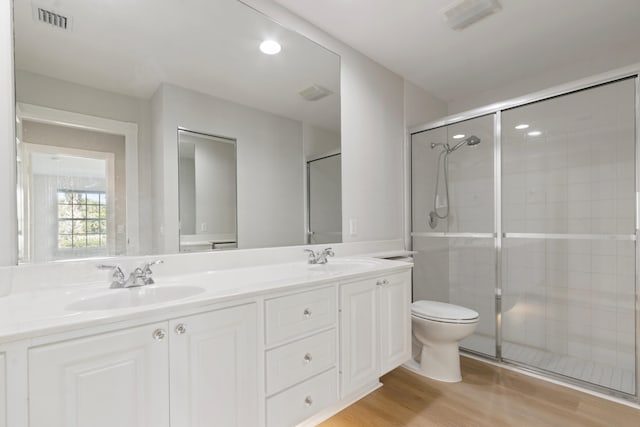 bathroom with toilet, vanity, wood-type flooring, and walk in shower