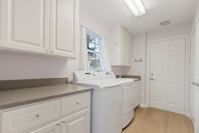 laundry room featuring independent washer and dryer, cabinets, and light hardwood / wood-style floors