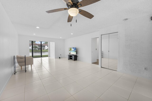 unfurnished living room featuring light tile patterned floors, a textured ceiling, and ceiling fan