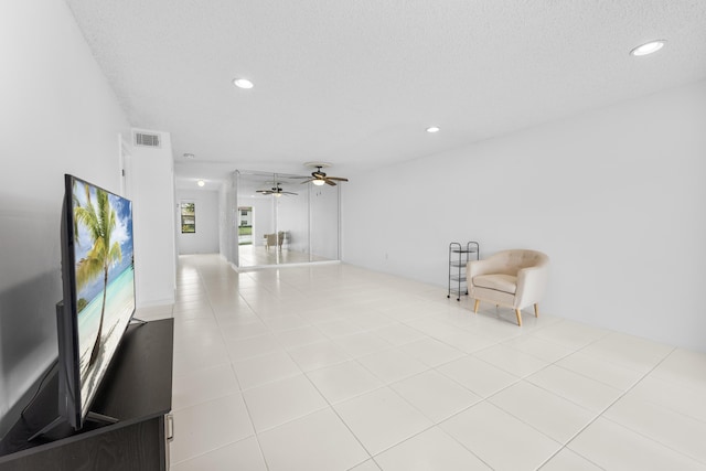 interior space featuring ceiling fan, light tile patterned flooring, and a textured ceiling