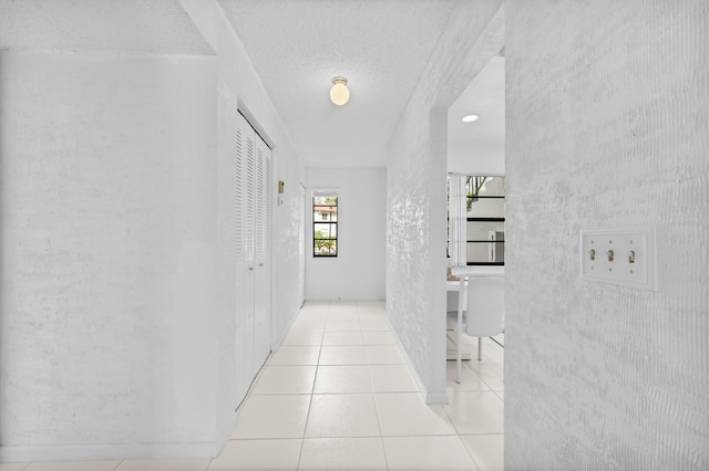 hall featuring light tile patterned floors and a textured ceiling