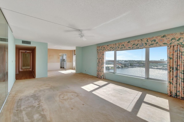 empty room with a water view, ceiling fan, and a textured ceiling