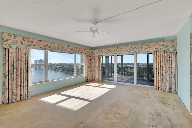 interior space featuring ceiling fan, a textured ceiling, and a water view