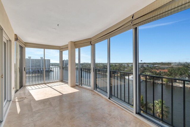 unfurnished room featuring light carpet, ceiling fan with notable chandelier, a water view, and a healthy amount of sunlight