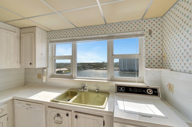 kitchen featuring dishwasher, sink, backsplash, range, and a water view