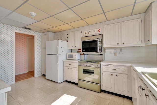 kitchen featuring white cabinetry, white appliances, and a drop ceiling