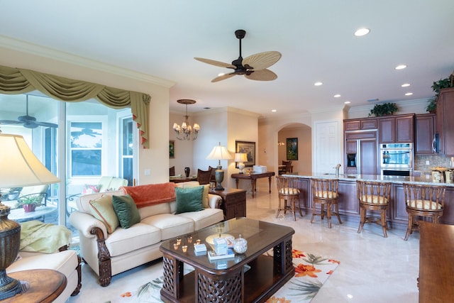 living room featuring ceiling fan with notable chandelier, ornamental molding, and sink