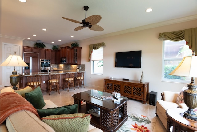 living room with ceiling fan, a healthy amount of sunlight, light tile patterned flooring, and ornamental molding