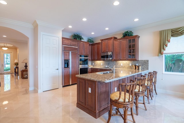 kitchen with kitchen peninsula, appliances with stainless steel finishes, tasteful backsplash, ornamental molding, and sink