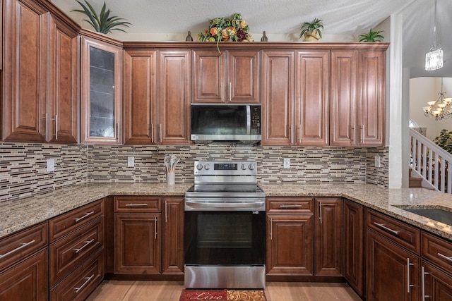 kitchen with appliances with stainless steel finishes, a textured ceiling, and light hardwood / wood-style flooring