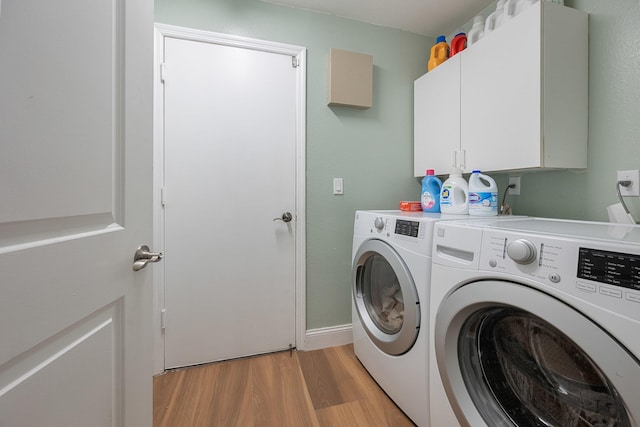 laundry area with washer and dryer, cabinets, and light hardwood / wood-style flooring