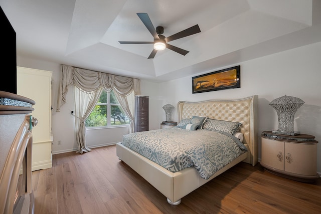 bedroom with a tray ceiling, ceiling fan, and hardwood / wood-style flooring