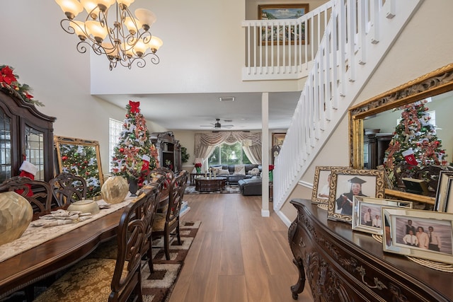 interior space with wood-type flooring, ceiling fan with notable chandelier, and a high ceiling