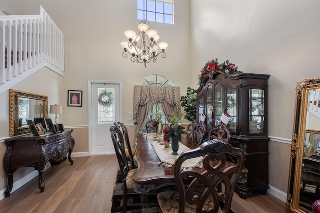 dining area with a high ceiling, hardwood / wood-style flooring, and a notable chandelier