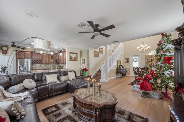 living room featuring ceiling fan with notable chandelier, light hardwood / wood-style flooring, and sink