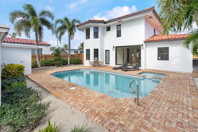 back of property featuring a fenced in pool and a patio