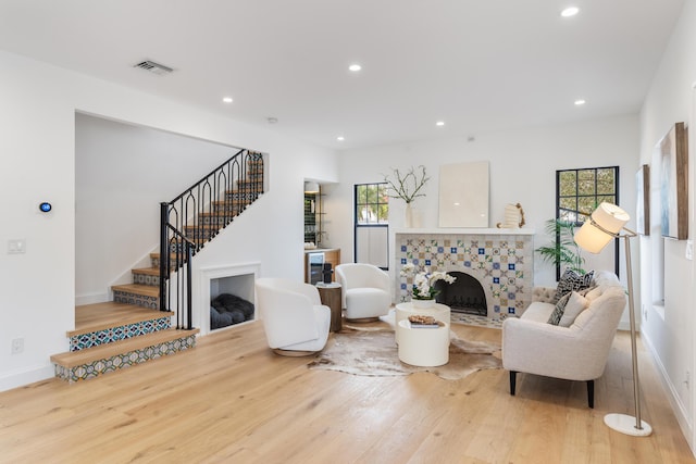 living room with a wealth of natural light, wood-type flooring, and a tile fireplace