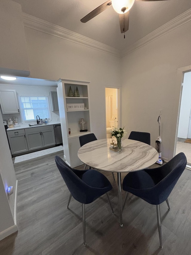 dining room with ceiling fan, a towering ceiling, crown molding, light hardwood / wood-style flooring, and sink