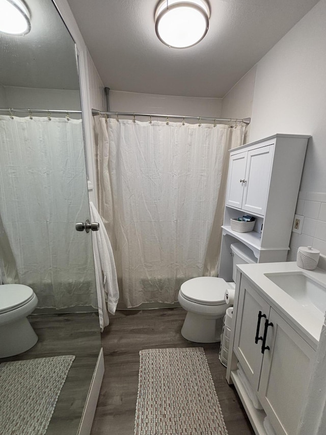 bathroom with hardwood / wood-style flooring, toilet, and vanity