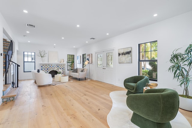 living room with a tile fireplace and light wood-type flooring