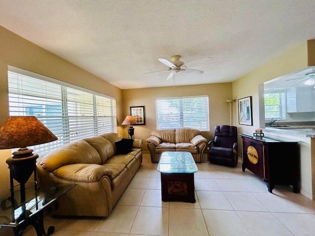 tiled living room with ceiling fan, sink, and a textured ceiling