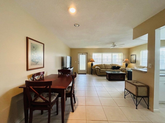 tiled dining area with a textured ceiling and ceiling fan