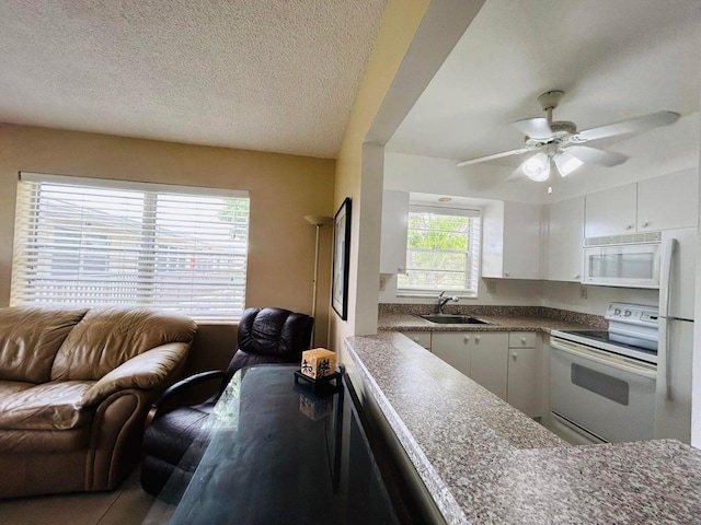 kitchen with white cabinetry, sink, ceiling fan, a textured ceiling, and white appliances