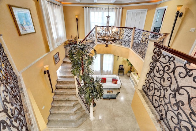 stairs with a chandelier, a high ceiling, and ornamental molding